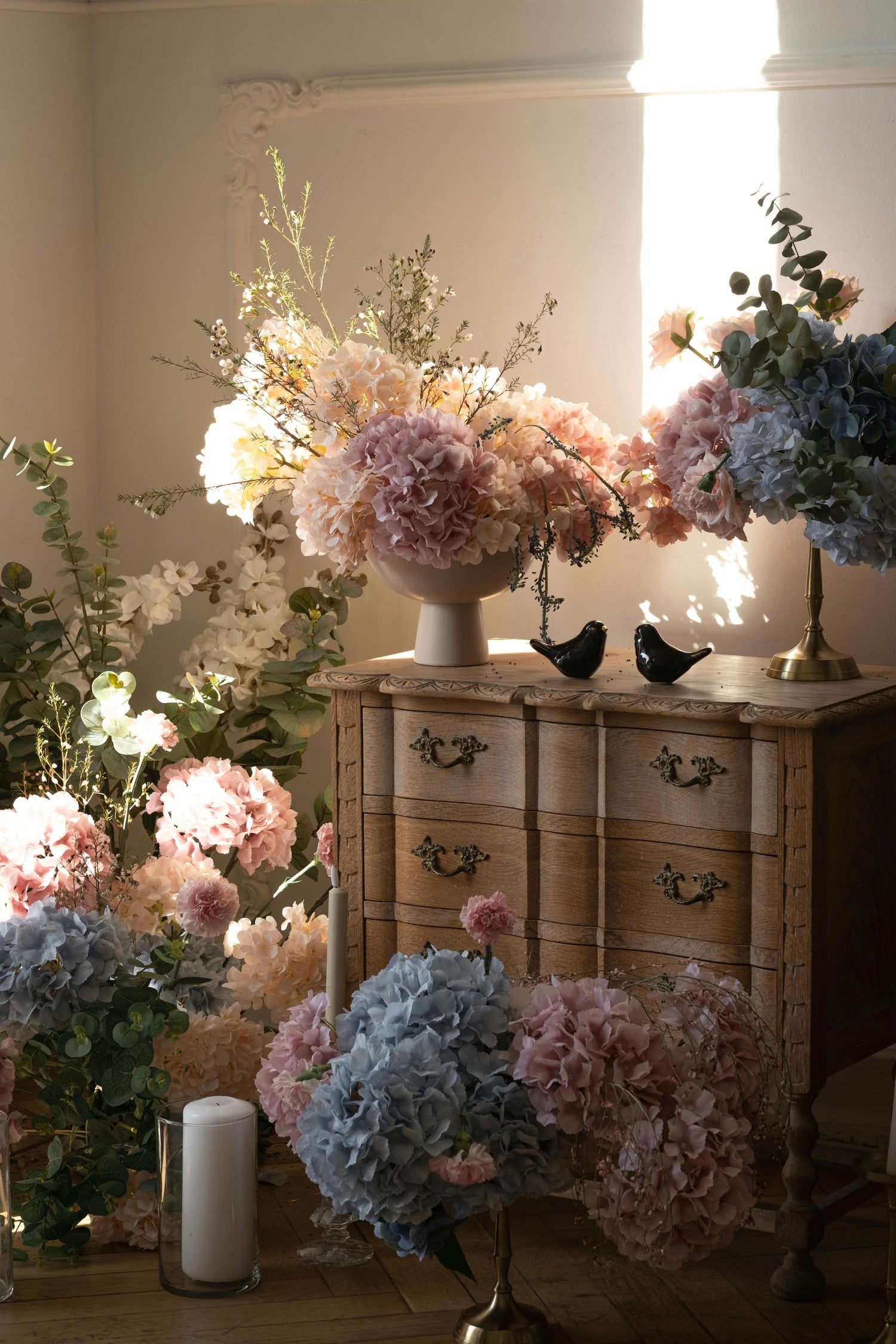 Elegant artificial flower arrangement on a vintage dresser with pastel-colored hydrangeas and greenery, creating a timeless interior decor.