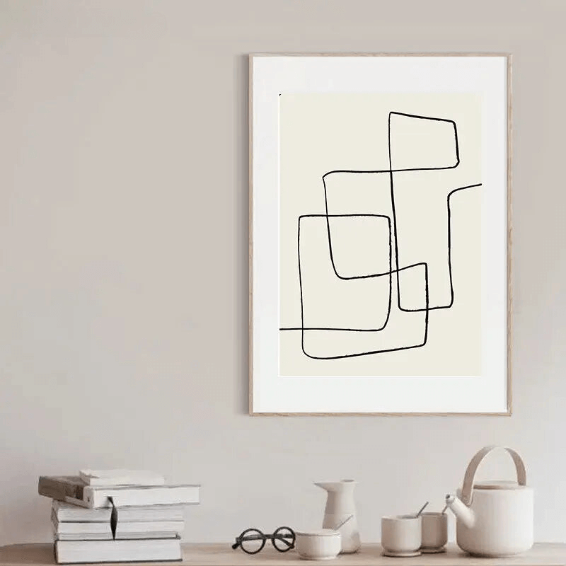 Tableau artistique abstrait noir et blanc suspendu dans un intérieur moderne avec décoration épurée et livres empilés