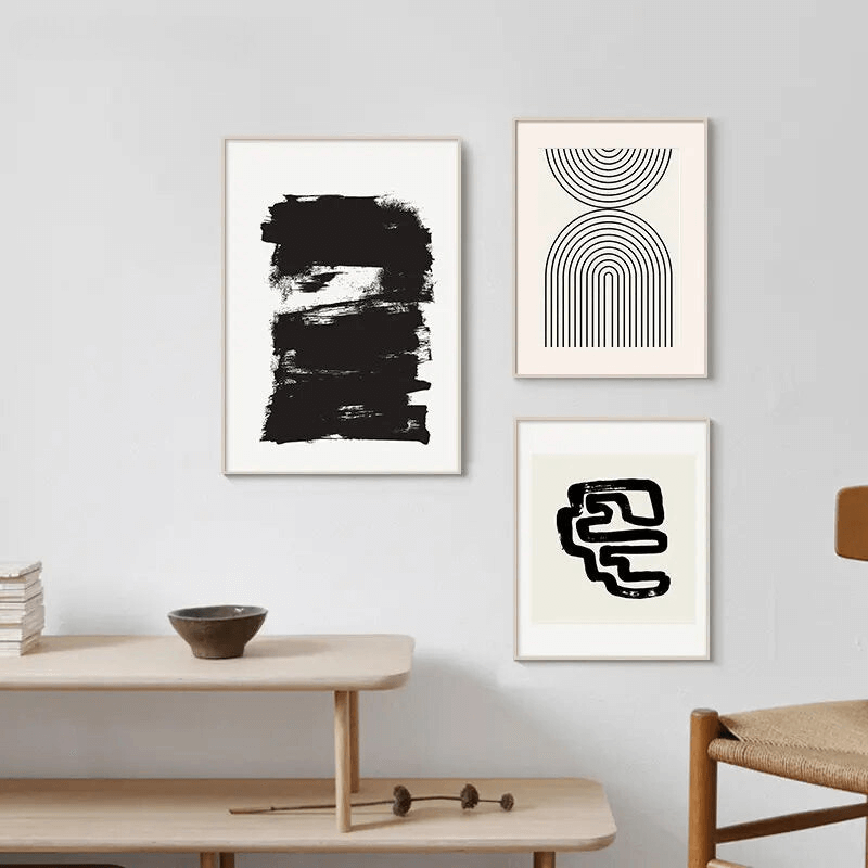 Ensemble de tableaux artistiques abstraits Noir & Blanc sur mur blanc, ajoutant une touche moderne à une pièce contemporaine.