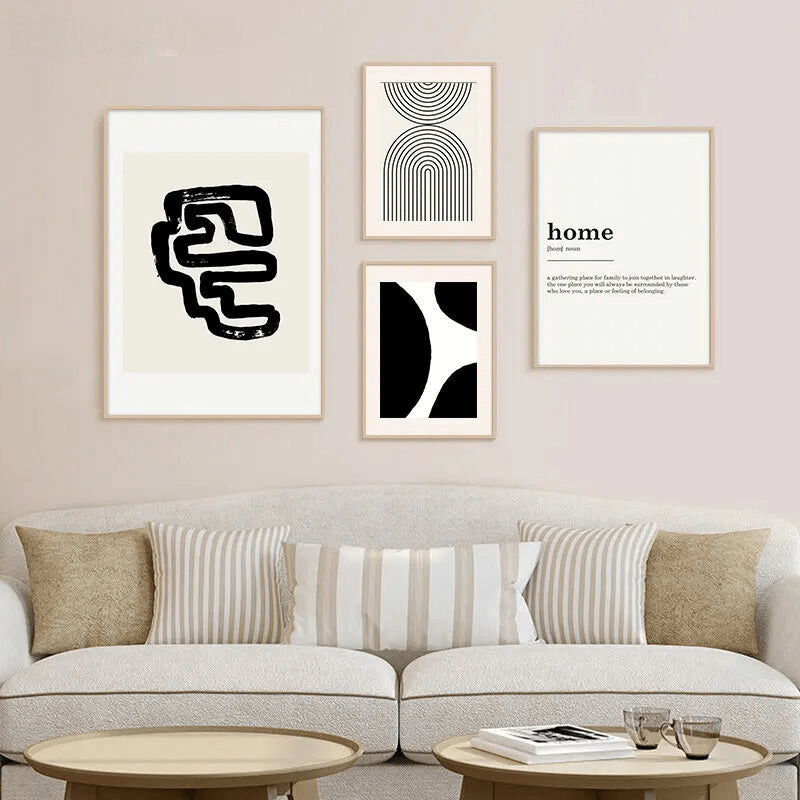 Tableau artistique abstrait noir et blanc dans un intérieur moderne au-dessus d'un canapé avec coussins rayés et tables basses.