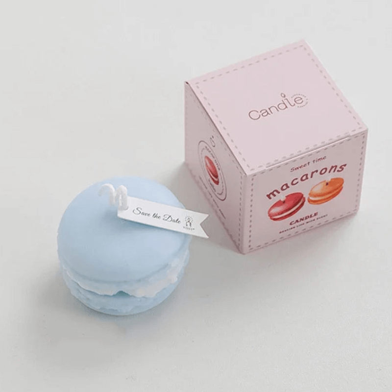 Bougie macaron parfumée bleue avec boîte rose, aromathérapie gourmande et décoration élégante.