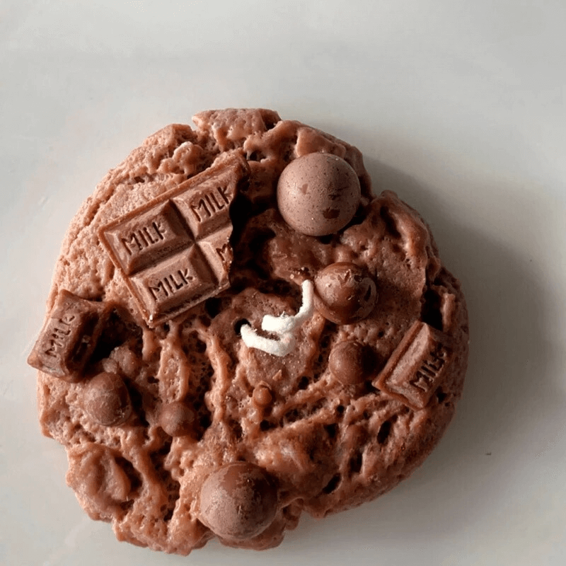 Bougie parfumée en cire de soja en forme de cookie au chocolat avec des morceaux de chocolat, décoration gourmande.