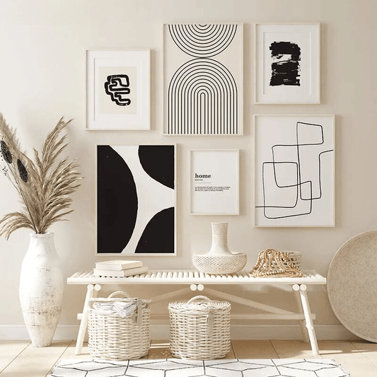 Mur de cadres artistiques abstraits noir et blanc dans un intérieur moderne avec des paniers en osier et un banc en bois.