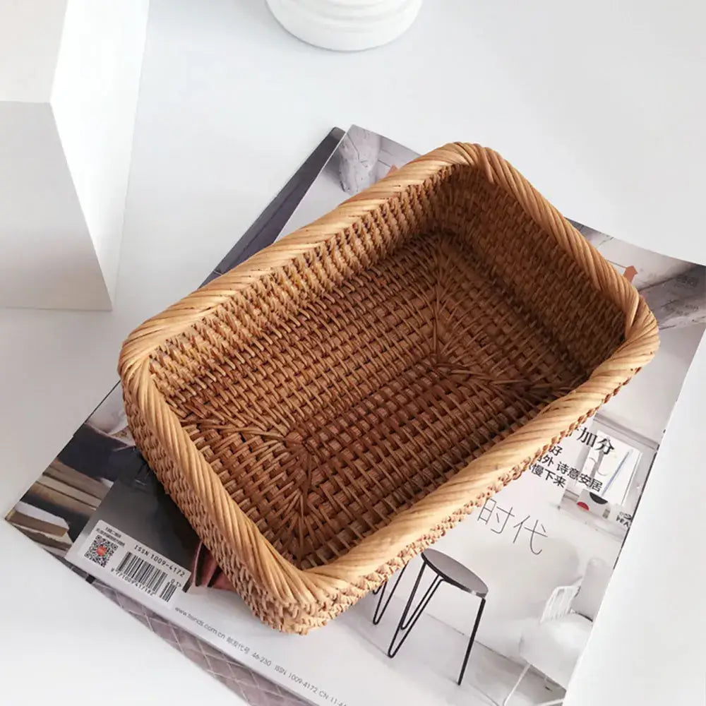 Panier de rangement en osier tressé rectangulaire, élégant et éco-responsable, posé sur des magazines pour une décoration intérieure stylée.