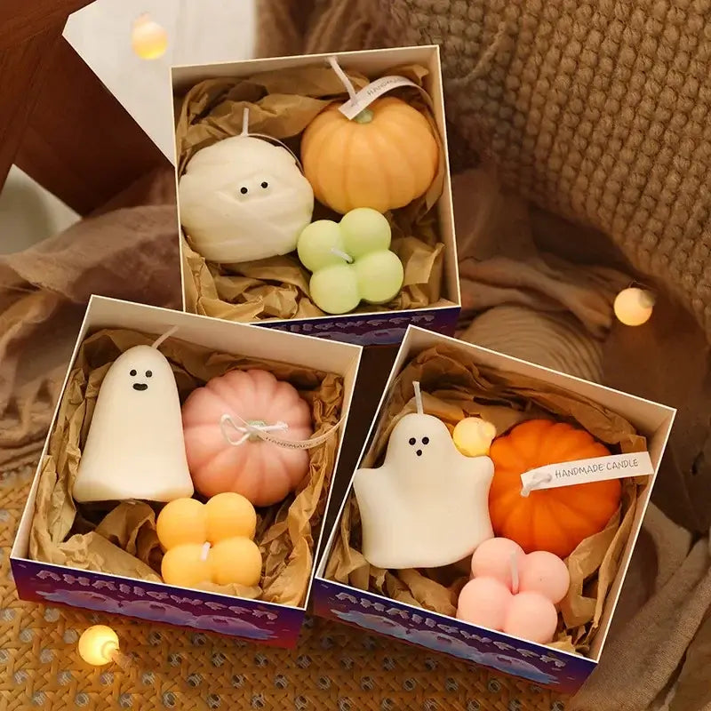 Three boxes of Halloween aromatherapy candles shaped like pumpkins and ghosts with colorful decorative accents arranged festively.