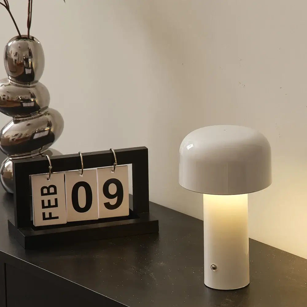 Lampe de Table LED Mini Champignon élégante avec éclairage réglable, posée sur une table noire à côté d'un calendrier moderne affichant le 9 février.