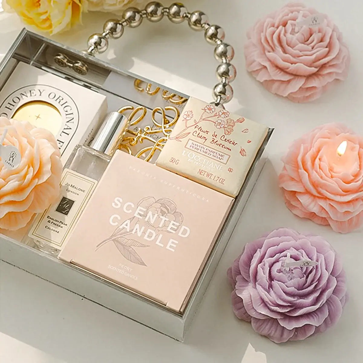 Scented rose-shaped candles in a decorative box with additional aromatherapy items.