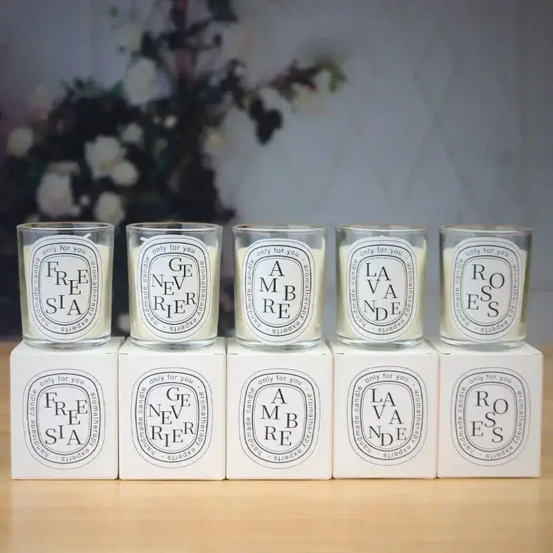 Collection of scented glass candles in different fragrances including Freesia, Genevrier, Ambre, Lavande, and Roses.