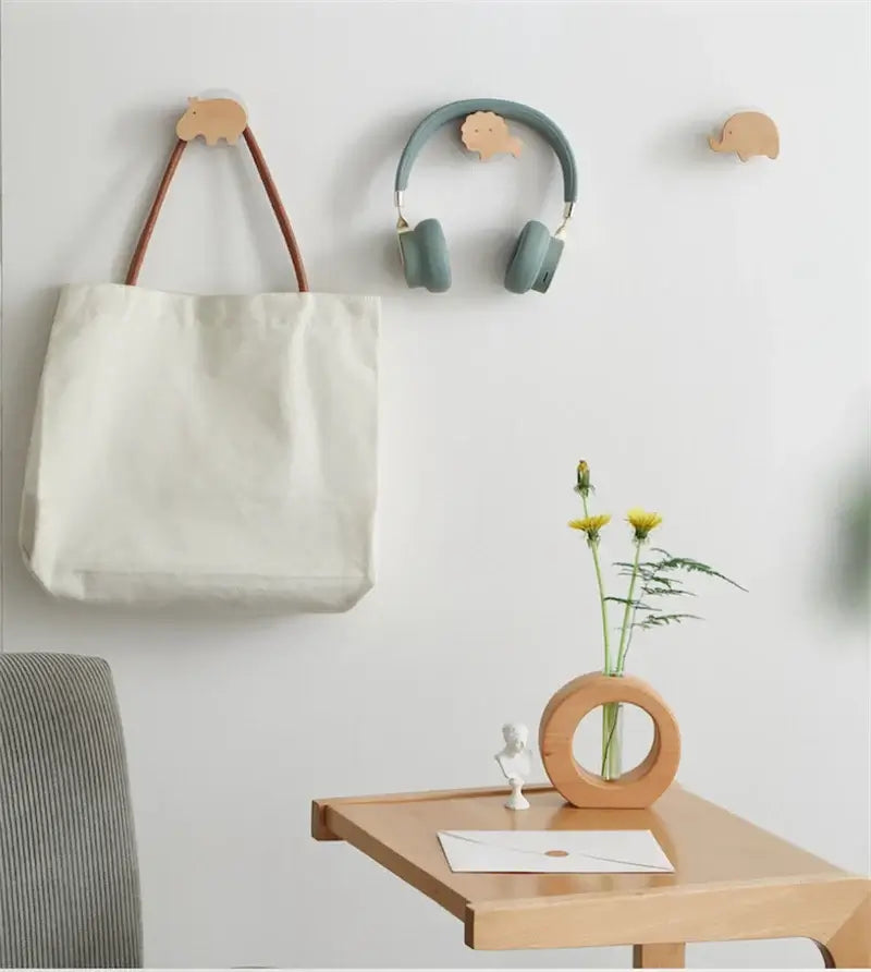 Crochets en bois animal avec sac et casque accrochés, décoration murale ludique dans une pièce moderne