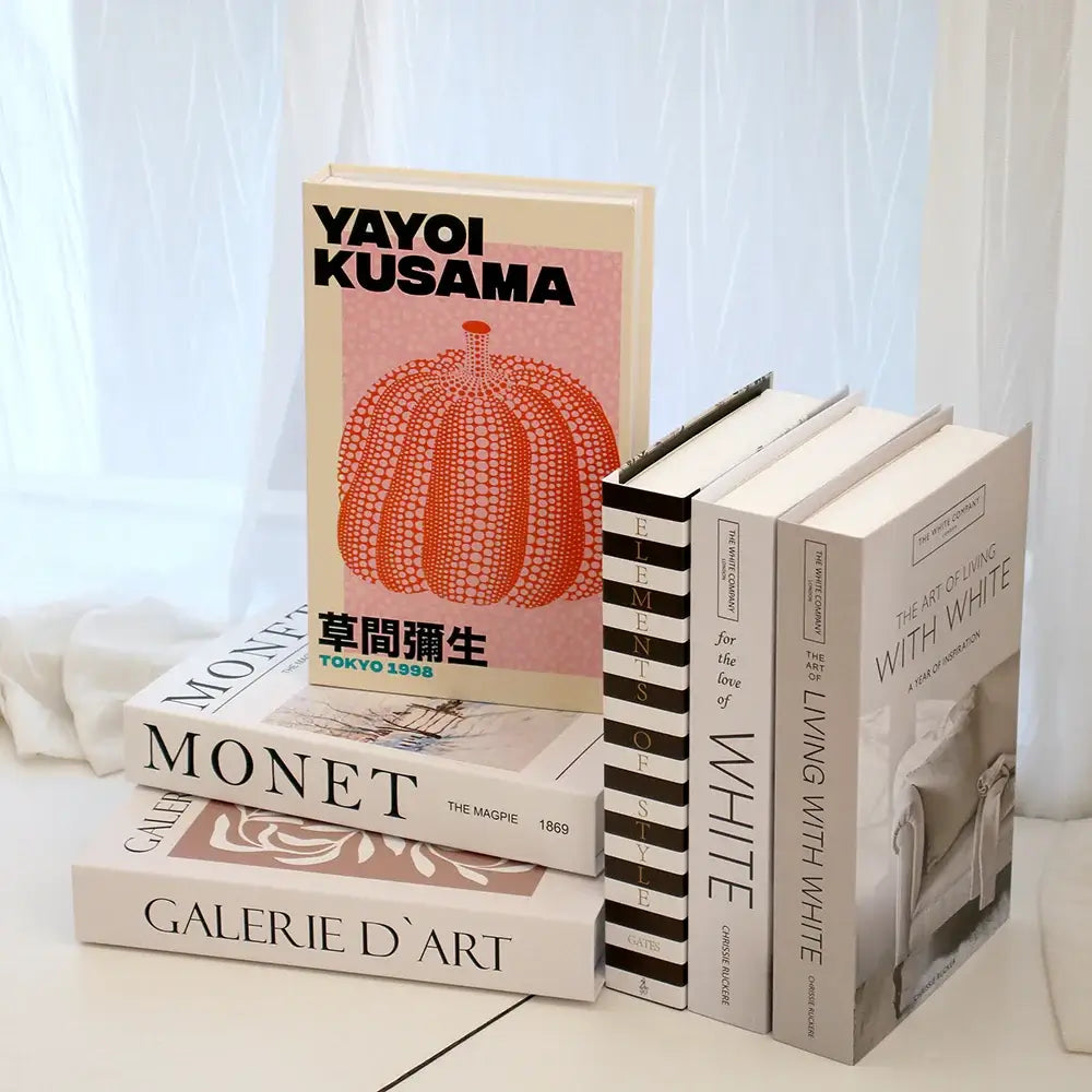 Faux livres de décoration moderne comprenant "Yayoi Kusama" et "Monet" sur une table design blanche.