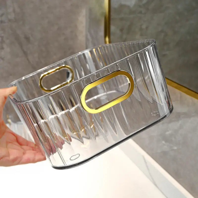 Transparent textured storage box with gold accents being held, ideal for organizing small items with an elegant touch.