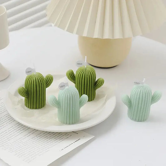 Decorative cactus-shaped scented candles in green and pastel colors on a white table, perfect for modern home decor.