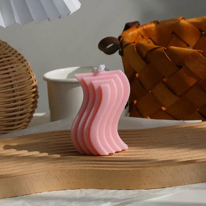 Bougie d'aromathérapie zigzag en cire de soja rose sur une table en bois, entourée de décoration intérieure naturelle et apaisante.