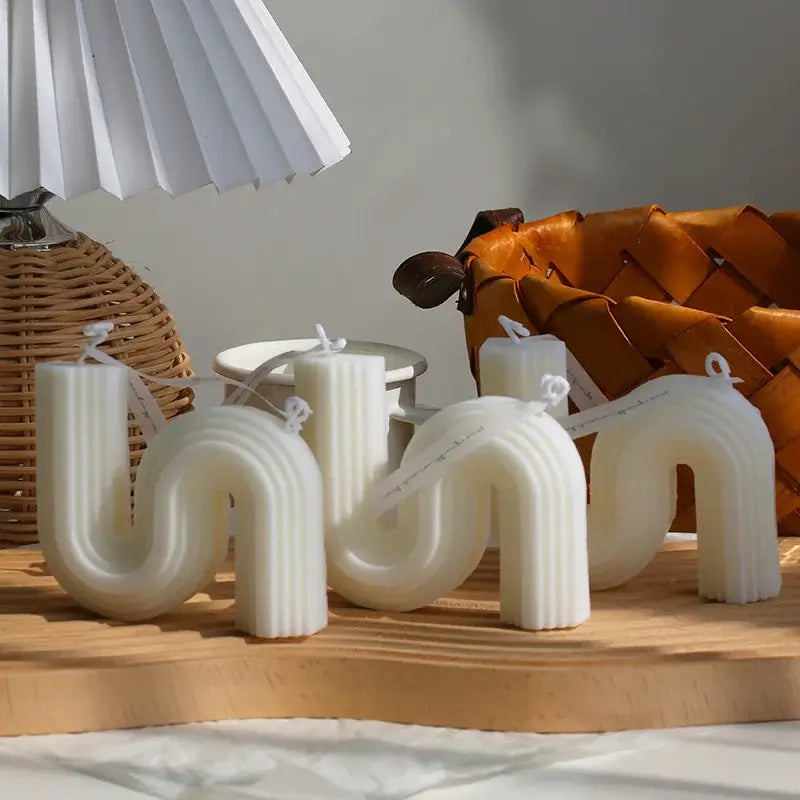 Bougies d'aromathérapie zigzag en cire de soja, design sculptural blanc, disposées sur une table en bois avec une décoration intérieure.