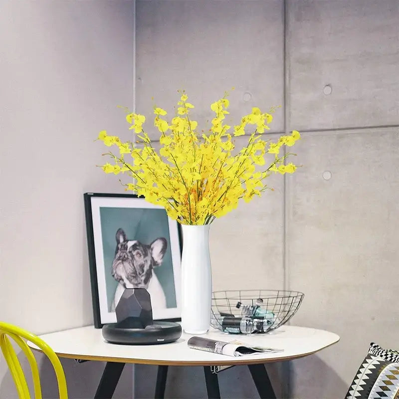 Yellow Orchid Bouquet in white vase on table, with dog photo and decorative items, adding elegance to modern interior decor.