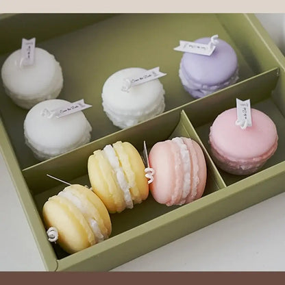 Macaron-shaped scented candles in pastel colors arranged in a green box