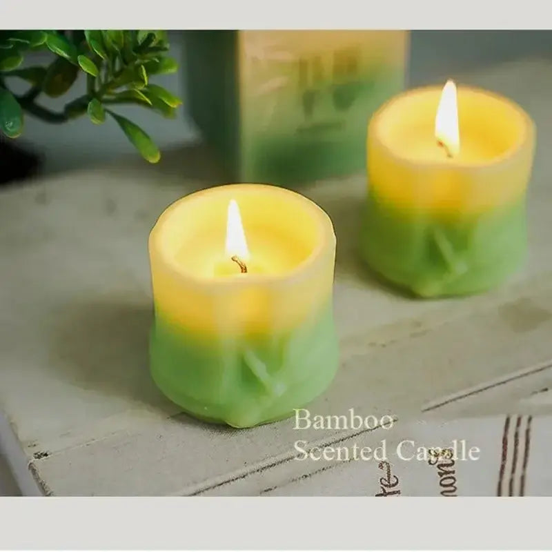 Two lit bamboo style scented candles on a table, adding elegance and serenity to the space.