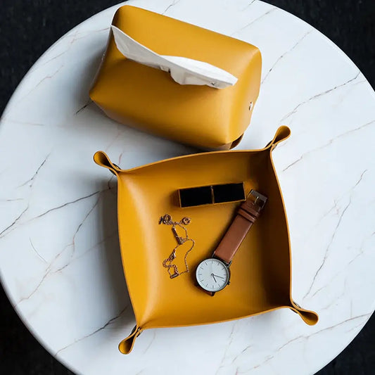 Vide poche en cuir synthétique écologique jaune avec montre, porte-clés et boîte à bijoux sur table en marbre