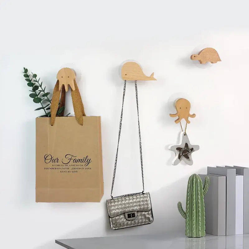 Crochets en bois animal fixés au mur, tenant un sac, une pochette, et une étoile décorative, ajoutant une touche ludique et pratique à la décoration intérieure.