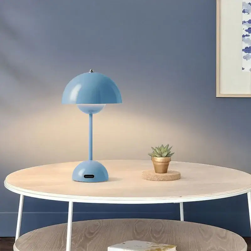 Lampe de table LED design champignon bleue sur une table dans une pièce moderne avec une plante succulente et un éclairage doux