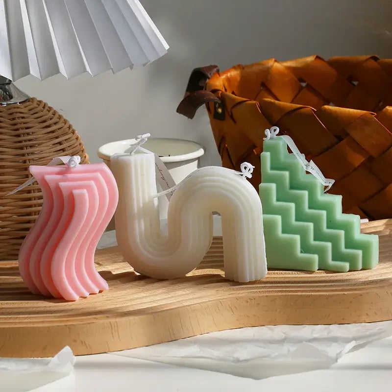 Bougies d'aromathérapie en cire de soja avec design wavy, zigzag et sculptural dans des teintes pastel sur une table en bois.