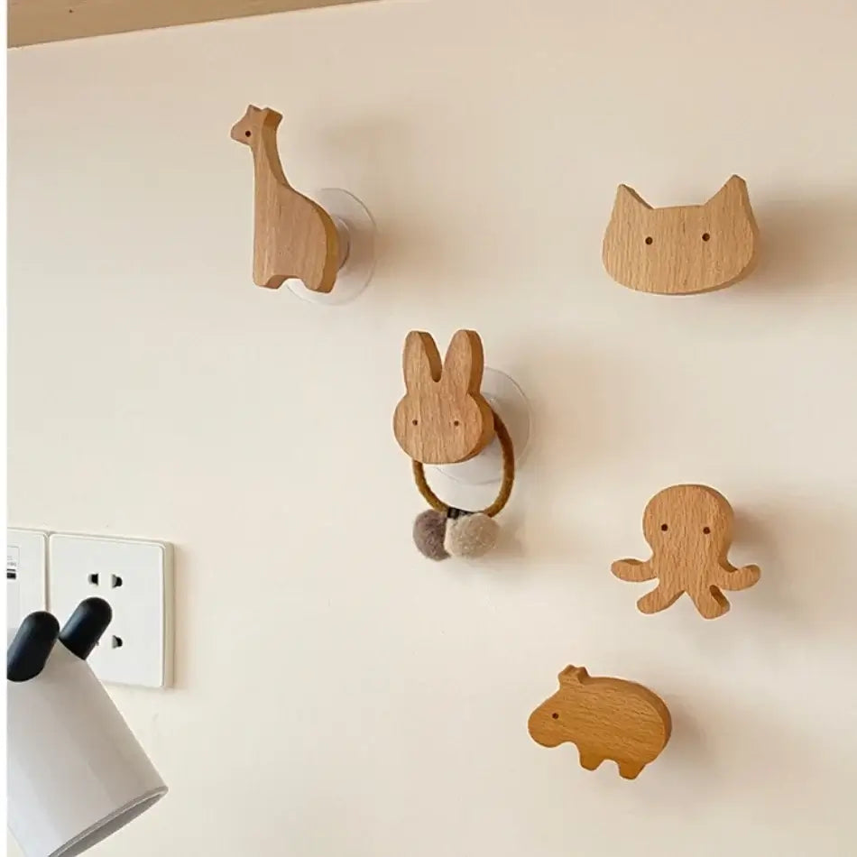 Crochets de porte en bois en forme d'animaux dont une girafe, un chat, un lapin, une pieuvre et un hippopotame accrochés au mur.