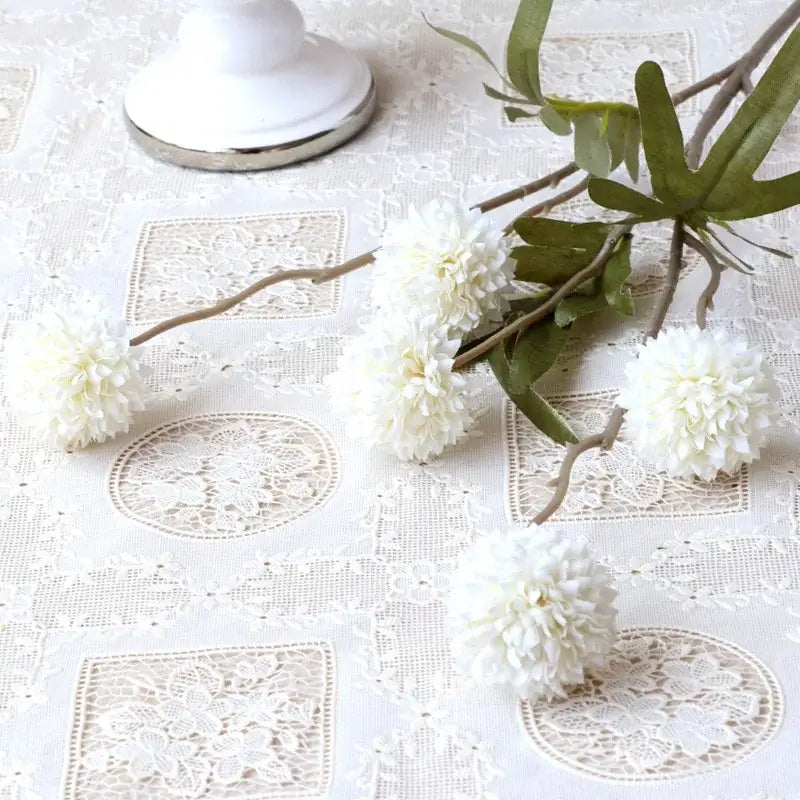 Bouquet de fleurs artificielles pissenlit pour décoration mariage et maison sur une nappe en dentelle.