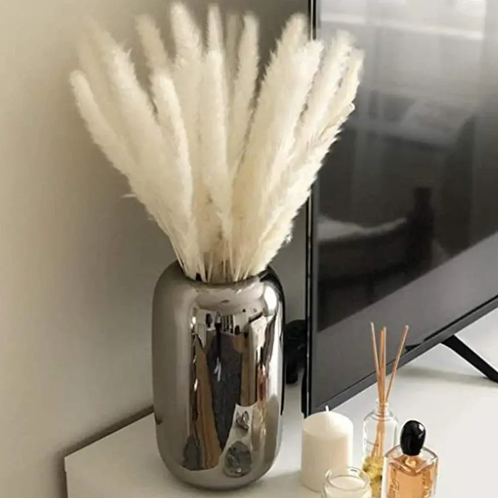 Bouquet de fleurs séchées de pampas naturelles dans un vase moderne argenté, parfait pour la décoration intérieure élégante et festive.