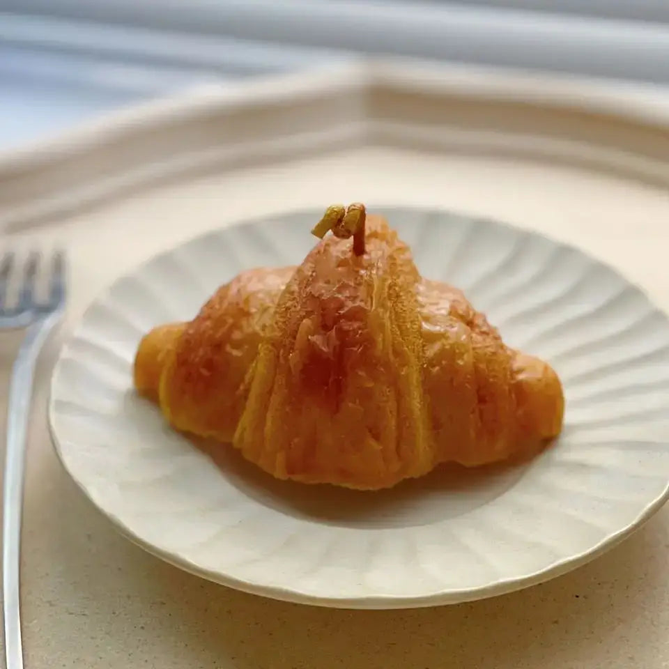 Bougie parfumée en forme de croissant sur une assiette raffinée, ajoutant une touche artistique et élégante à la décoration intérieure.