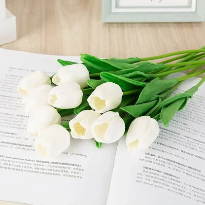 Bouquet de tulipes en soie blanche sur une table en bois, ajoutant une touche élégante à la décoration intérieure.