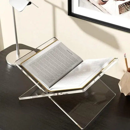 Support de livre en acrylique transparent exposant un livre ouvert sur un bureau moderne noir.