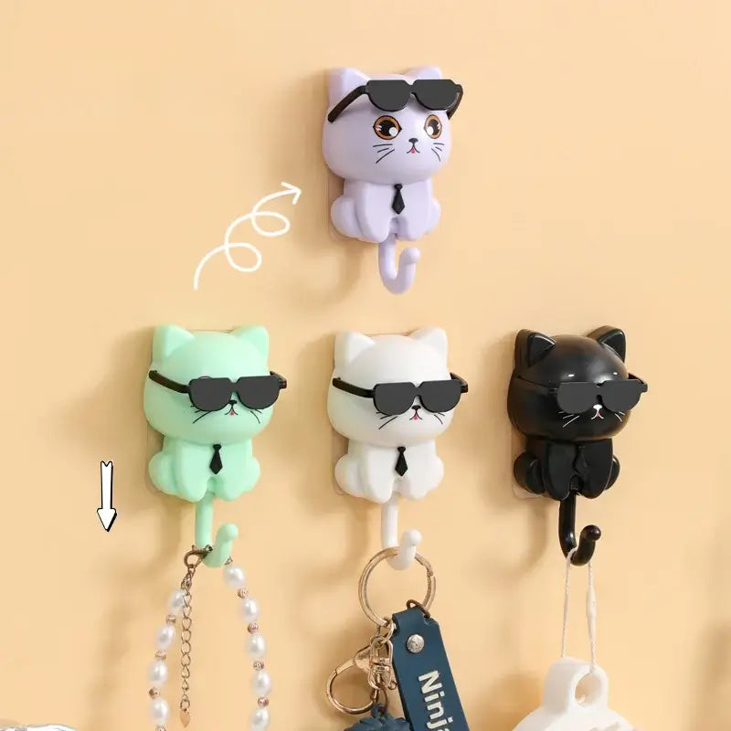 Cute cat-shaped accessory hooks in black, white, purple, and green colors, displaying sunglasses design, organizing keys and jewelry.