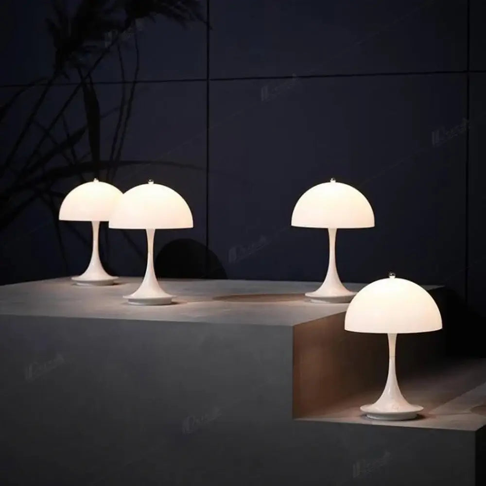 Quatre lampes de table LED modernes en aluminium blanc sur un escalier, éclairant un espace minimaliste et élégant