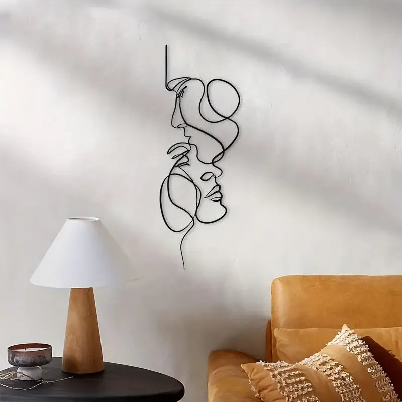 Modern metal wall art depicting two abstract faces above a cozy living room setup with a lamp and a sofa.