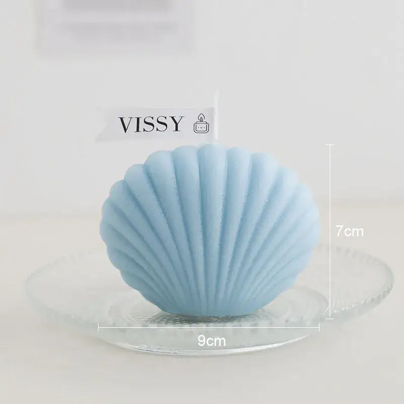 Bougie parfumée en forme de coquillage sur une assiette en verre, couleur bleue, dimensions 9cm x 7cm, marque Vissy.