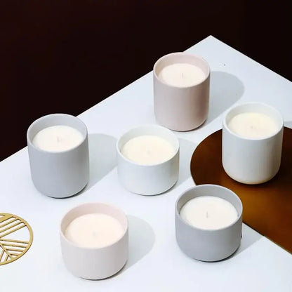 Bougeoirs en céramique avec couvercle en blanc, rose pâle et gris sur table blanche, apportent une touche d'élégance et de style à tout intérieur.