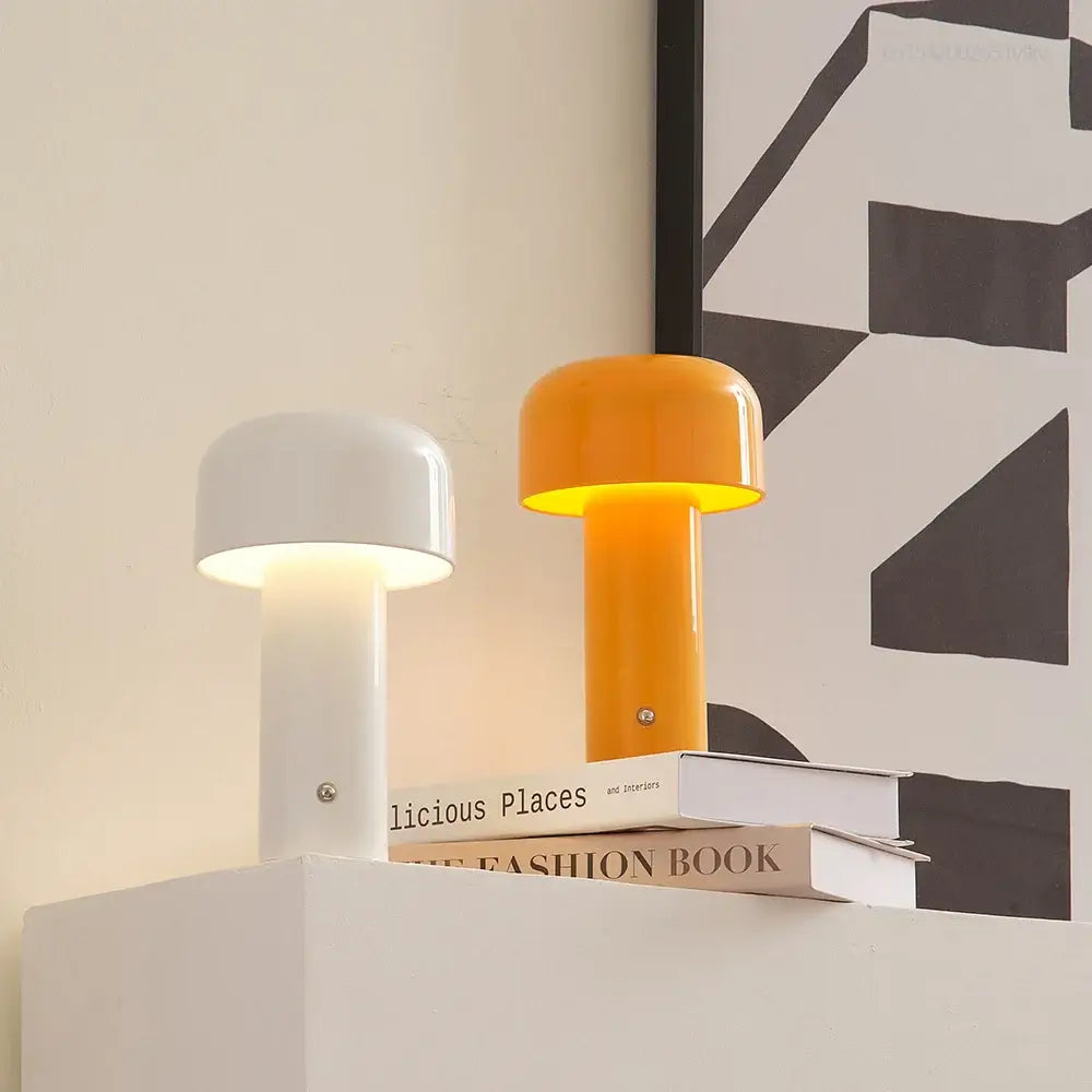 Lampe de table LED mini champignon blanche et orange sur une table avec des livres, décoration moderne et élégante.