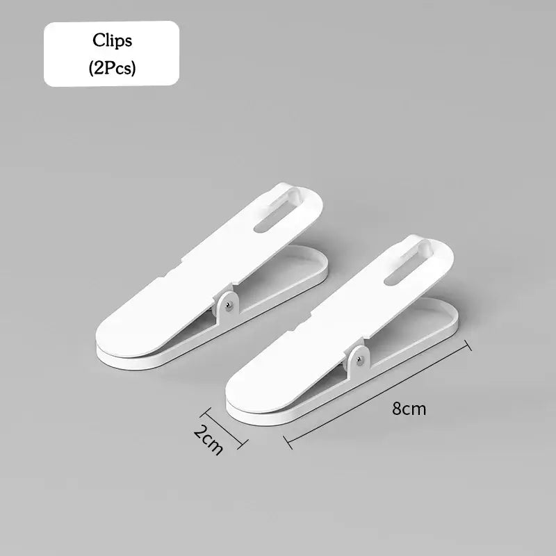 Two white plastic clips, each measuring 8cm by 2cm, for wall-mounted storage solutions from the Panneau de rangement mural & accessoires set