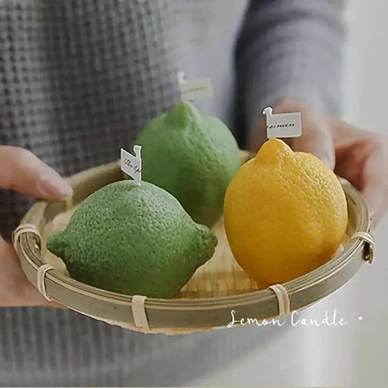 Handmade soy lemon-scented candles in the shape of green and yellow lemons on a wooden tray.