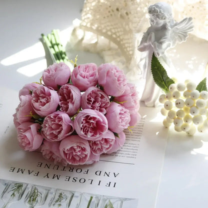 Bouquet de pivoines en soie rose réaliste avec 27 têtes de roses pour une décoration élégante, posé sur une table avec des accessoires décoratifs.