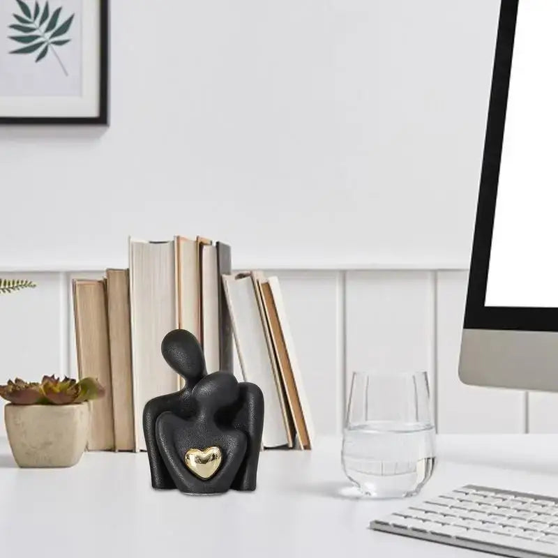 Ceramic couple hugging figurine with gold heart on desk, modern romantic home décor.