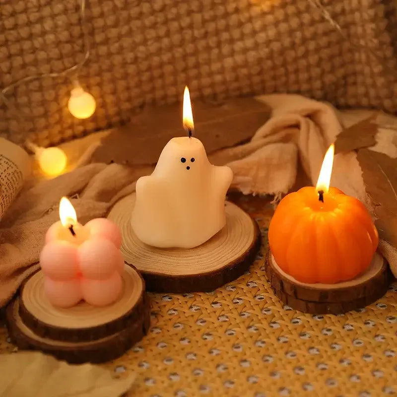 Bougies d'aromathérapie Halloween en forme de citrouille, fantôme et cube sur des supports en bois pour une ambiance festive et chaleureuse.