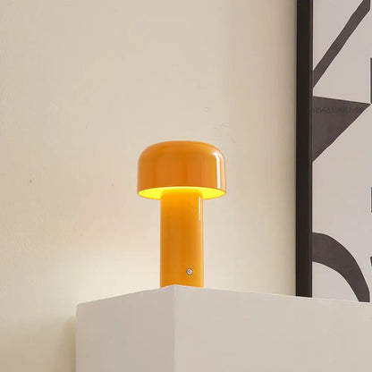 Lampe de table LED mini champignon orange sur une étagère, créant une ambiance moderne et apaisante dans une pièce minimaliste.