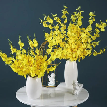 Élégant bouquet de fleurs d'orchidée jaune dans des vases blancs, ajoutant une touche sophistiquée à la décoration intérieure de maison ou de fête.