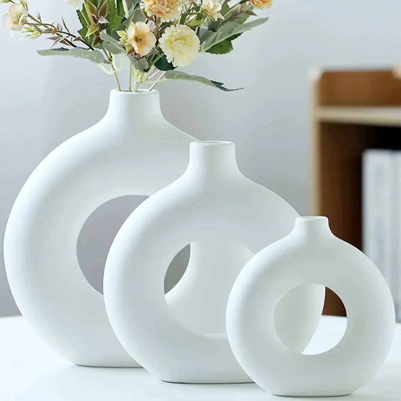 Three white ceramic donut vases, elegantly minimalist design, perfect for enhancing floral arrangements and modern interior decor.