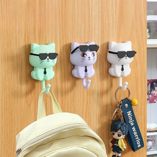 Porte-accessoires crochet chaton cartoon en vert, violet et blanc, avec lunettes de soleil, accroché à un mur en bois, parfait pour décorer.