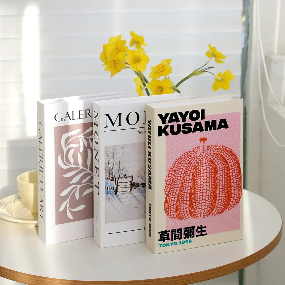 Decorative faux books with modern art designs on display table with yellow flowers