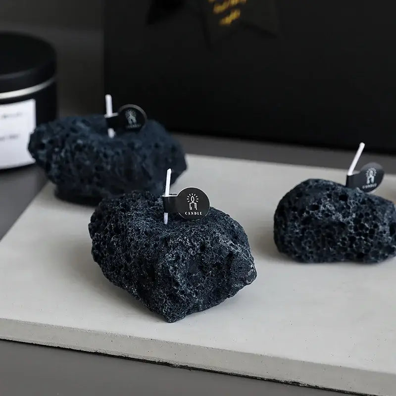 Bougie parfumée météorite élégante et originale en cire noire sur une surface blanche, ajoutant une touche unique et moderne à votre intérieur.