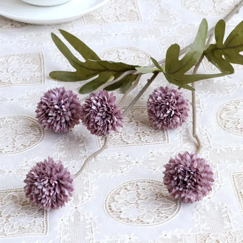 Bouquet de fleurs artificielles pissenlit violet sur nappe en dentelle blanche, décoration polyvalente pour mariage, maison et Noël.