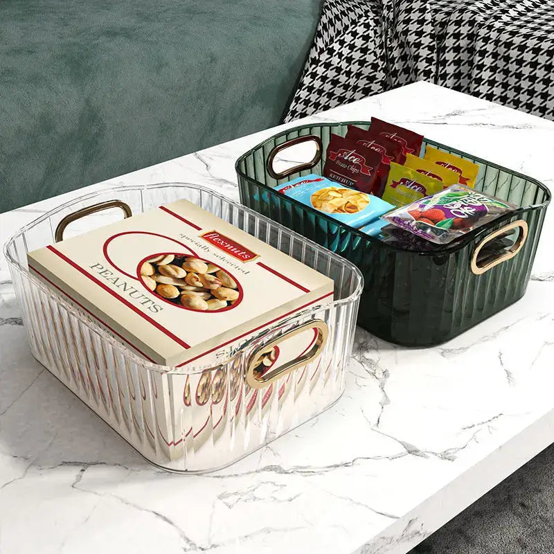 Transparent and green textured storage boxes on a marble table holding snacks and nuts, adding elegant organization to a living space.